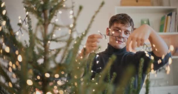 Fiatal Férfi Díszítő Karácsonyfa Led Fények Otthon Nyaralás Közben — Stock videók