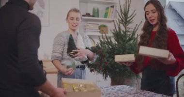 Kadın ve erkek arkadaşlar Noel süslemelerini evdeki masaya yerleştiriyorlar.