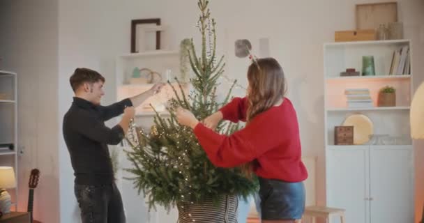 男男女女在客厅里用灯光装饰圣诞树 — 图库视频影像
