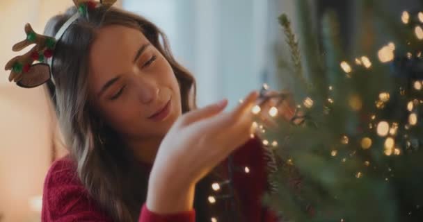 Усміхнена Жінка Регулює Освітлені Світлодіодні Ліхтарі Дереві Вдома Під Час — стокове відео