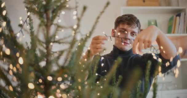 Fiatal Férfi Díszítő Karácsonyfa Led Fények Otthon Nyaralás Közben — Stock videók