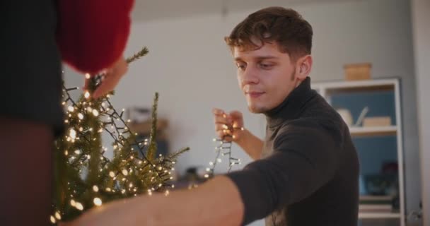 Junges Paar Mit Led Lichtern Schmückt Weihnachtsbaum Wohnzimmer — Stockvideo