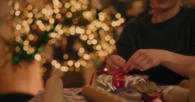 Noel tatilinde evde kurdeleyi hediye kutusuna bağlayan adamın orta kısmı.