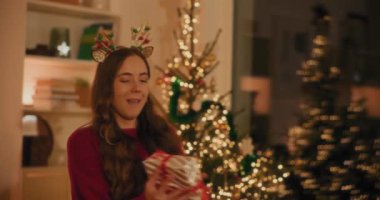 Mutlu genç bir kadın Noel tatili boyunca eve hediye atıyor.