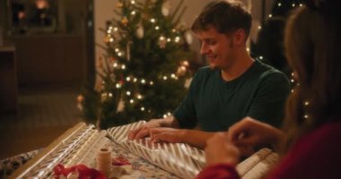 Gülümseyen genç adam Noel tatilinde bayan arkadaşının yanında oturuyor.