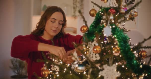 Mujer Joven Atando Adornos Navidad Árbol Casa Durante Las Vacaciones — Vídeo de stock