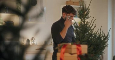 Genç adam Noel 'de evde dikilirken akıllı telefondan arıyor.