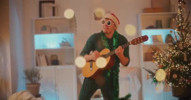 Handschuss Junger Mann Genießt Weihnachten Gitarrenzupfen Wohnzimmer — Stockvideo