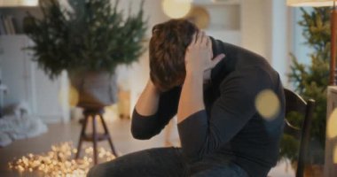 Depresyondaki genç adam Noel tatilinde evdeki oturma odasında oturuyor.
