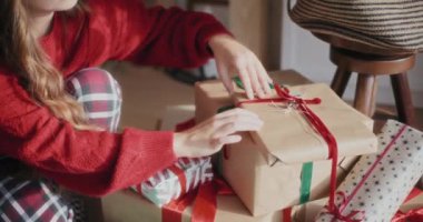 Parlak evde paketlenmiş Noel hediyeleri düzenleyen bir kadın.