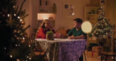 Genç adam, tatilde evde oturan kızgın kız arkadaşına Noel hediyesi veriyor.