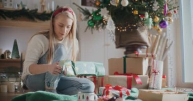 Evde Noel hediyesini paketlerken kağıt kesen güzel genç bir kadın.