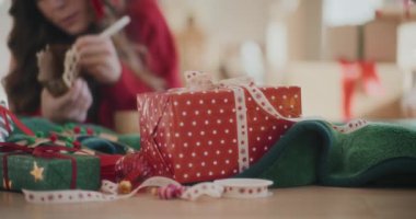 Evin arka planında kadın boyama karton evi olan çeşitli paketlenmiş Noel hediyeleri.