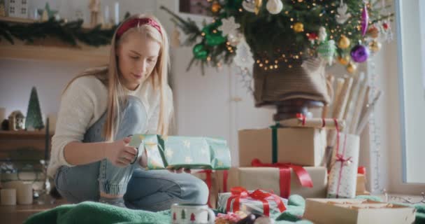 Beautiful Young Woman Cutting Paper While Wrapping Christmas Present Home — Stock Video