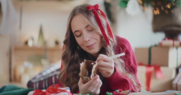 自宅でクリスマスの間に床に横たわっている間段ボールの家を着色する若い女性 — ストック動画