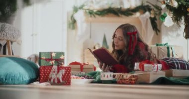 Noel 'de evde yerde yatarken kitap okuyan güzel bir genç kadın.