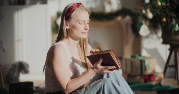 クリスマス中に明るい日差しで本を持ちながら目を閉じた美しいリラックスした女性 — ストック動画
