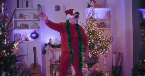 Exhilarated Young Man Santa Hat Sunglasses Dancing Illuminated Home Christmas — Stock Video