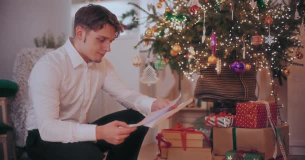 Jovem Feliz Lendo Carta Enquanto Agacha Por Presentes Natal Árvore — Vídeo de Stock