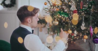 Evde süslü Noel ağacına takılan iyi giyimli bir adamın yan görünüşü