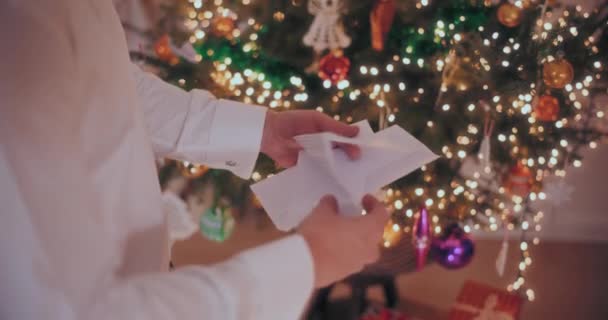 Middensectie Van Man Openingsbrief Met Versierde Kerstboom Achtergrond Thuis — Stockvideo