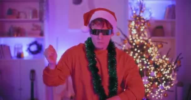 Jonge Man Santa Hoed Zonnebril Dansen Versierd Huis Tijdens Kerstmis — Stockvideo