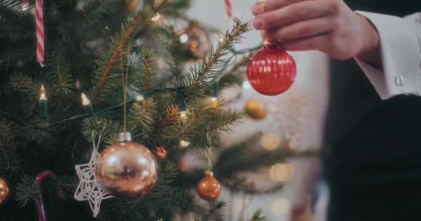 Обрезанная Мужская Рука Висит Красной Безделушкой Рождественской Елке Дома — стоковое видео
