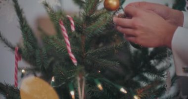 Kırpılmış erkek elleri Noel ağacını gümüş takılarla süslüyor.
