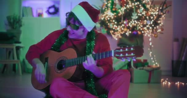 Excited Young Man Santa Hat Sunglasses Playing Guitar While Sitting — Stock Video