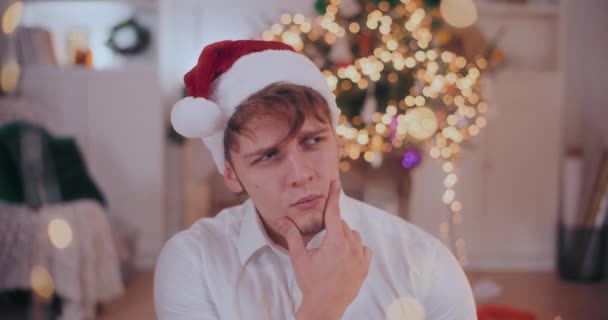 Joven Reflexivo Con Mano Barbilla Con Sombrero Santa Durante Navidad — Vídeo de stock