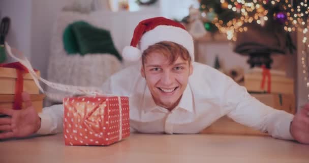 Porträt Eines Glücklichen Jungen Mannes Mit Weihnachtsmütze Der Weihnachtsgeschenke Schiebt — Stockvideo