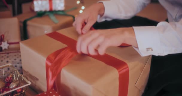 Evde Paketlenmiş Noel Hediyesine Kırmızı Kurdele Bağlayan Genç Adamın Orta — Stok video