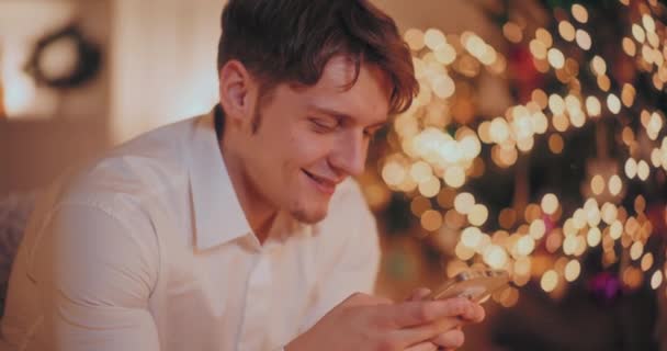 Счастливый Молодой Человек Улыбается Время Использования Смартфона Освещенном Доме Время — стоковое видео