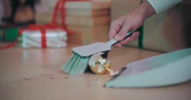 クリスマス中に自宅のハードウッドフロアのダストパンで壊れたバブルピースを収集する男のクロップされた手 — ストック動画
