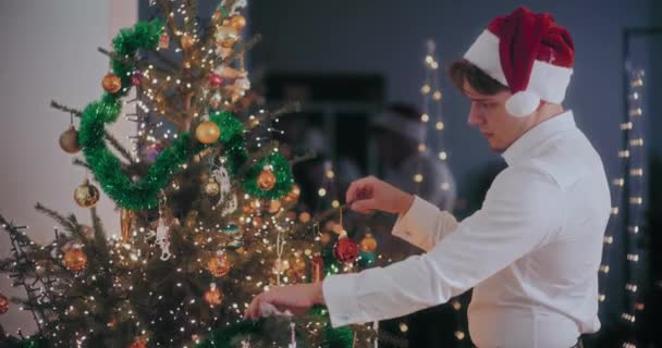 Young Man Formals Santa Hat Decorating Christmas Tree Tinsels Ornaments — Stock Video