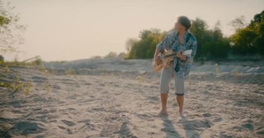 Olumlu gitarist elinde gitar tutuyor açık havada gitar çalıyor dans ediyor ve yürüyor.