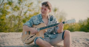 Olumlu gitarist elinde gitar tutuyor açık havada gitar çalıyor dans ediyor ve yürüyor.