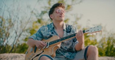 Olumlu gitarist elinde gitar tutuyor açık havada gitar çalıyor dans ediyor ve yürüyor.