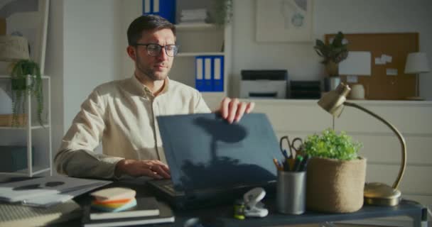 若い男性起業家がラップトップを開き オフィスの机に座って仕事を始める — ストック動画