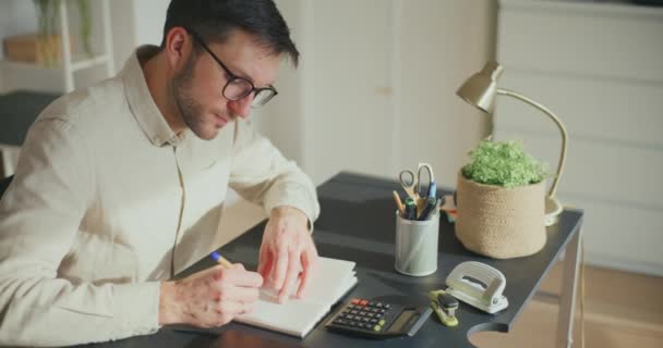 沮丧的男性创业者坐在办公桌前 用计算器编写财务报告 — 图库视频影像