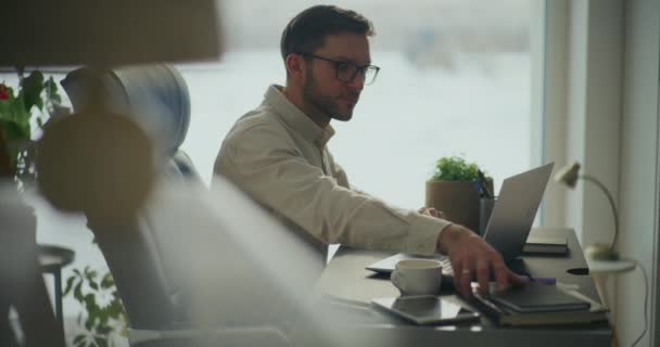 オフィスの机に座っているノートパソコンで日記を拾うビジネスマンの側面 — ストック動画