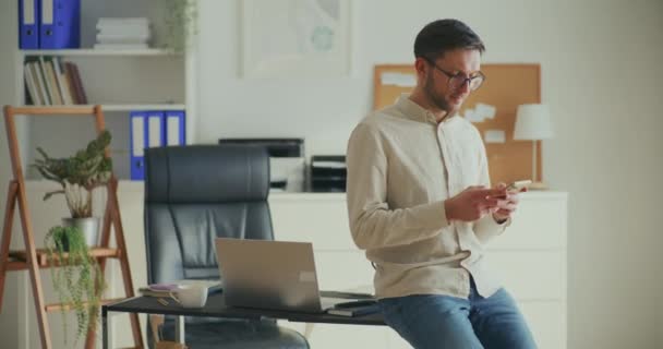 Junge Männliche Unternehmerin Nutzt Smartphone Während Sie Sich Büro Schreibtisch — Stockvideo