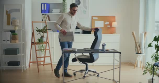 オフィスに到着しながら ノートパソコンとスマートフォンをデスクに保つ若い男性ビジネスプロフェッショナル — ストック動画