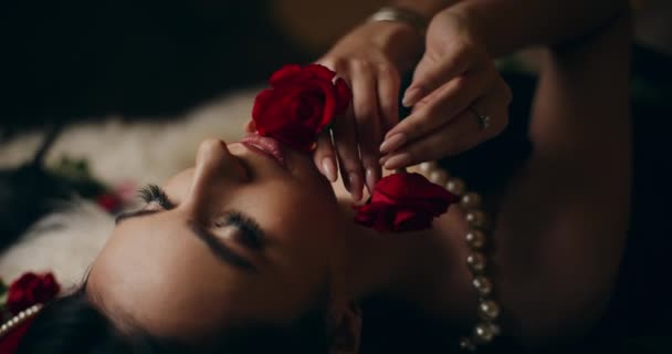 迷人的年轻女子躺在床上闻着红玫瑰的香味 用红玫瑰抚摸着脸的特写镜头 — 图库视频影像