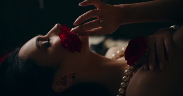 性感年轻女子卧床时 紧闭双眼 用红玫瑰触摸脸部和身体的特写镜头 — 图库视频影像