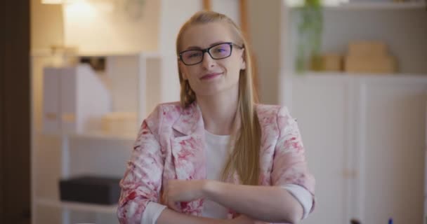 Portret Uśmiechniętej Młodej Blond Bizneswoman Okularach Siedzącej Rękami Skrzyżowanymi Biurze — Wideo stockowe