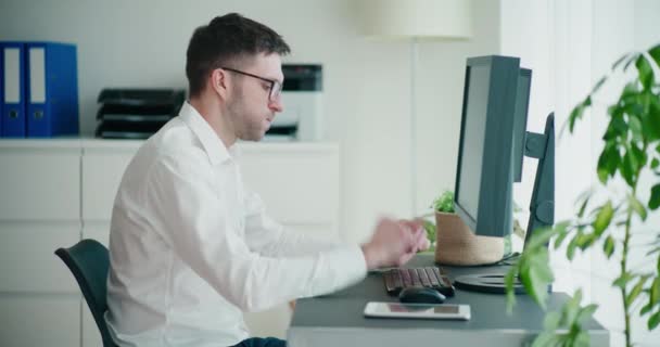 企業のオフィスにデジタルタブレットとコンピュータで座っている間 不安な若いビジネスマンのタップデスクの側面 — ストック動画