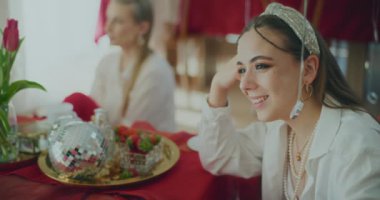 Evde Galentines Günü kutlamaları sırasında masada oturan mutlu genç kadın konuşuyor.