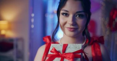 Galentines Günü 'nde elinde hediye paketi tutan gülümseyen genç bir kadının portresi.