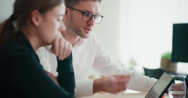 stock video Young businessman and businesswoman discussing strategy over digital tablet while sitting in office